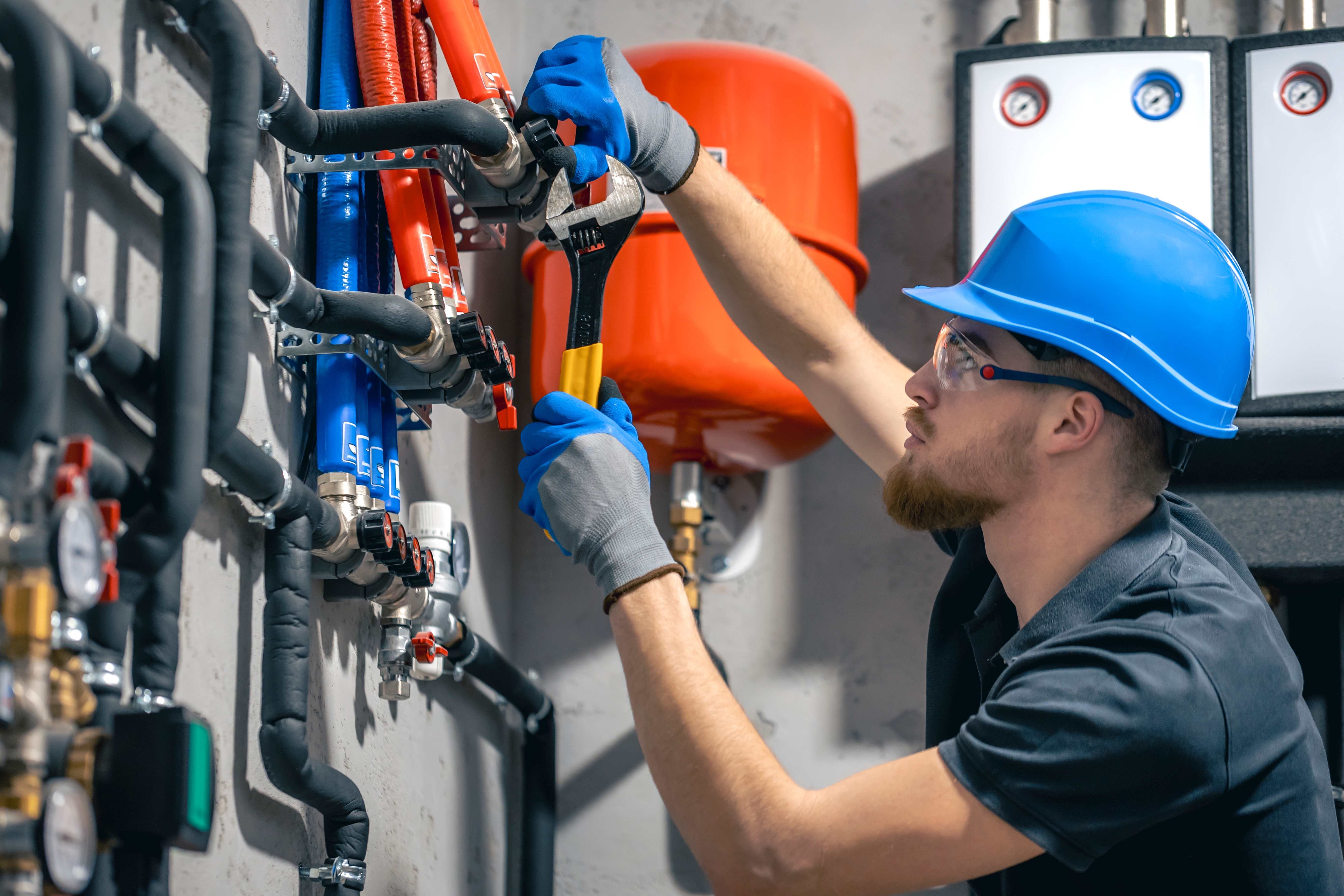 Licensed plumber tightening a valve on a water heater manifold in Corona, CA